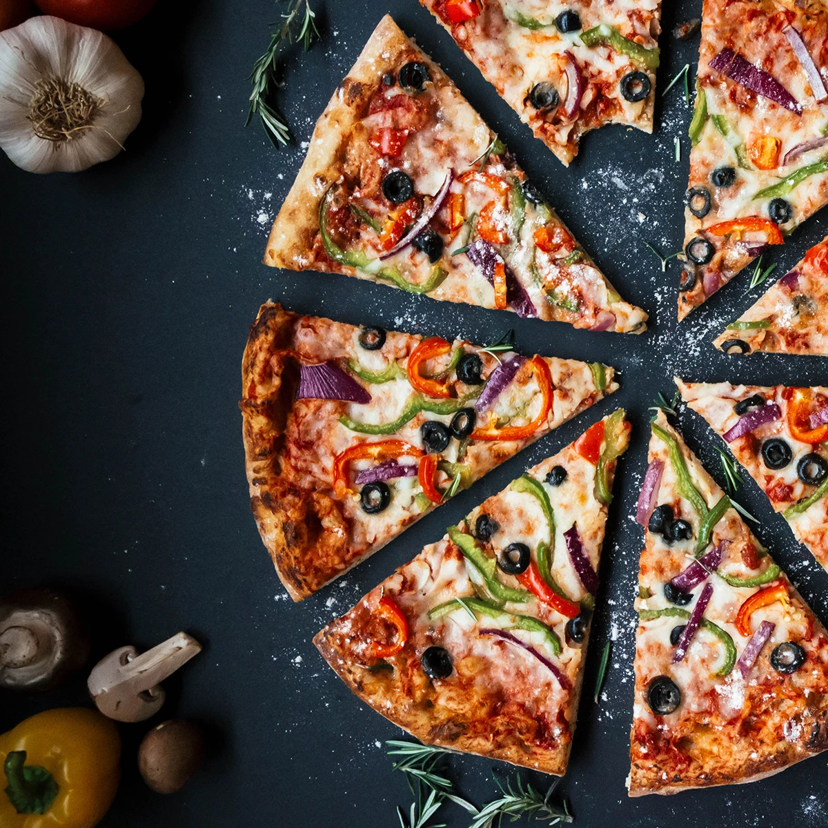 Eine in 8 Teile geschnittene Pizza mit Paprika und Oliven belegt